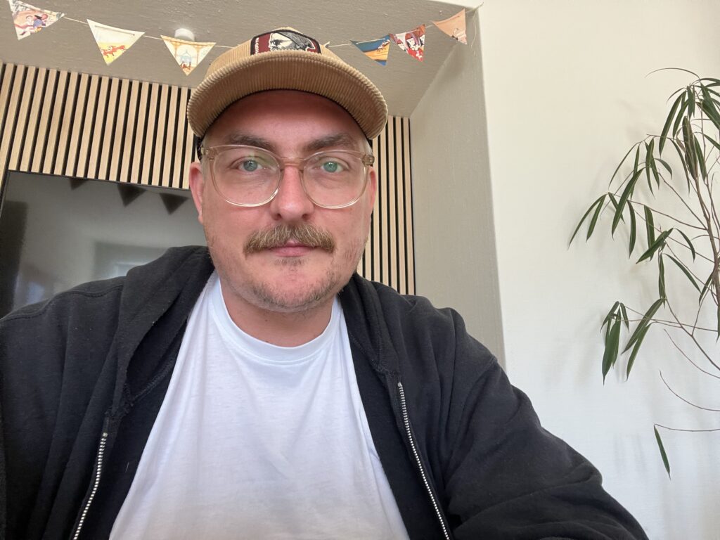 Michael Hedam i kasket og hvid T-shirt smiler til kameraet