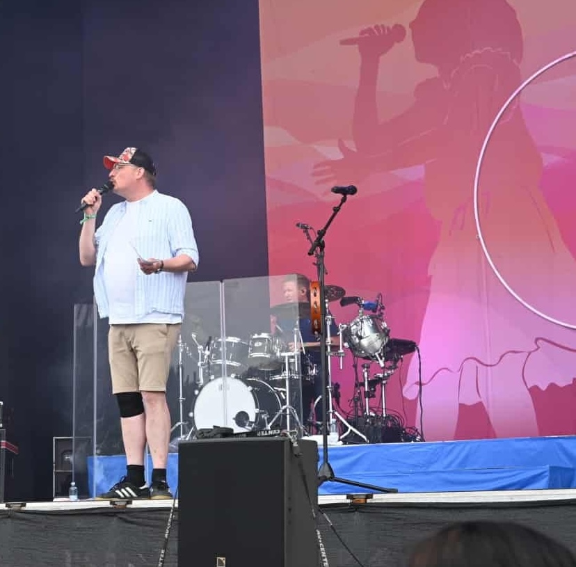 Michael Hedam som konferencier med mikrofon på en udendørs scene